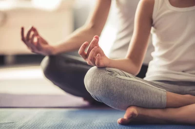 Cropped image of young woman and her little daughter doing yoga together at home